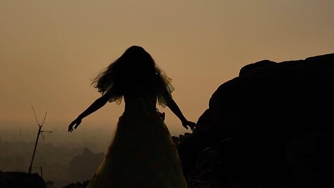 Girl dancing in the sunset at a mountain code