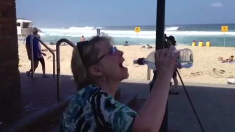 A Woman Tries To Drink From A Water Bottle Without Touching The Spout