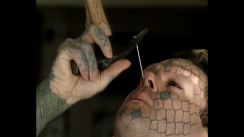 Lizardman Hammers Nail Up Nose