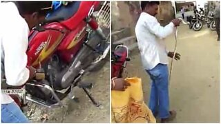 Mann trekker en slange ut av en motorsykkel