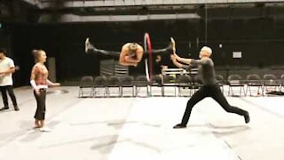 Acrobat goes through hoop while doing split leap