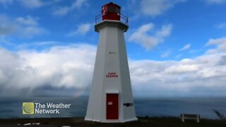 Rainbow peeks through fluffy clouds at the lighthouse