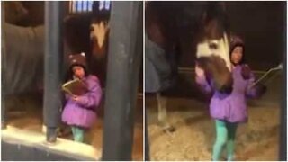 Suloinen pikkutyttö lukee hevoselle tarinan joka päivä