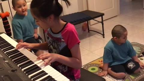 Kid Plays Piano While Her Twin Brothers Dance