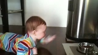 Baby 'swims' across floor to reach cat food bowl