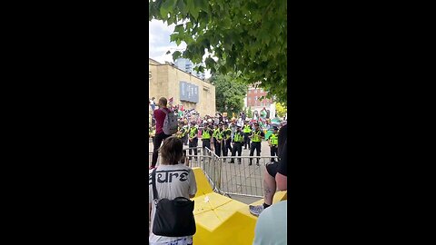 Muslim standing amongst the far left and behind a line of police threatening to "rape your mum"