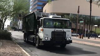 Waste Management roll off truck driving bye.