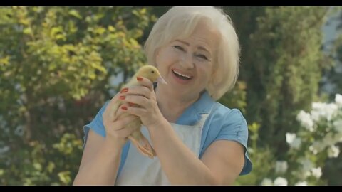 Happy senior woman holding duckling and smiling at camera Portrait of cheerful Caucasian blond lady