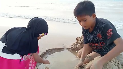 Bermain pasir dan ombak di pantai dengan kakak dan adik