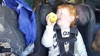 Une petite fille s'endort en mangeant sa pomme