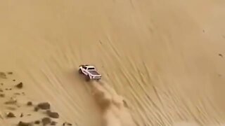 Full throttle truck drives up insanely steep sand dune