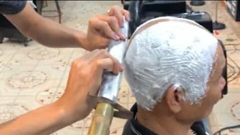 Barber shaves his client's head with a sword