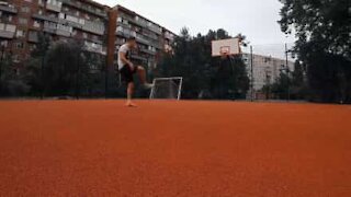 Jovem encesta bola de basquetebol com os pés