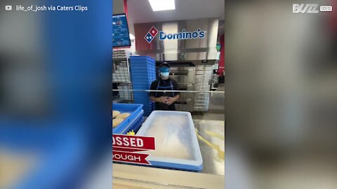 Un employé de Domino’s Pizza prépare une pizza les yeux bandés