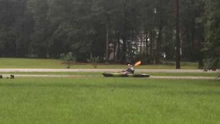 Man kayaks floodwater in garden