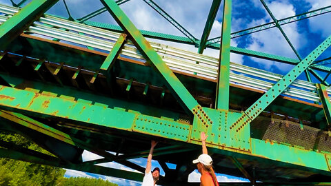 Pontoon boat slips under low metal bridge