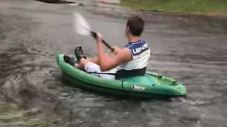 Young man goes kayaking on flooded street