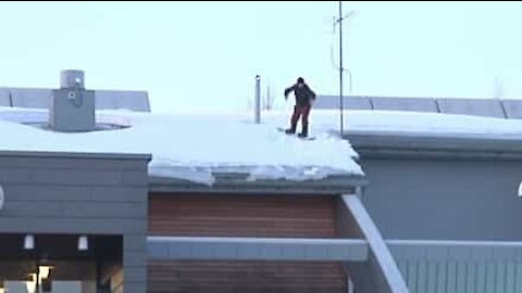 Snowboarder use roof as ramp