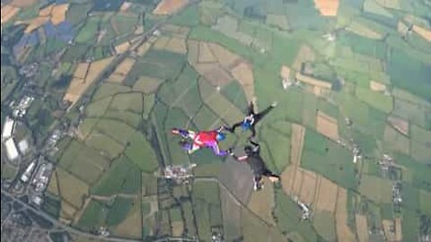 Friends hold onto each other while skydiving