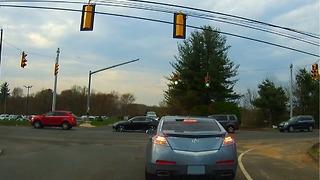 Car muscles his way through blocked intersection