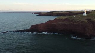 Flying Drone over Water by a Lighthouse