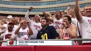 Sad Michigan fan surrounded by Badgers fans at Camp Randall Stadium