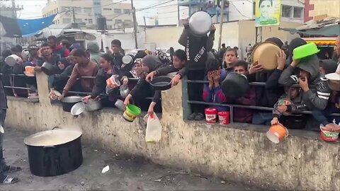 Palestinians wait with containers for food distribution in Rafah