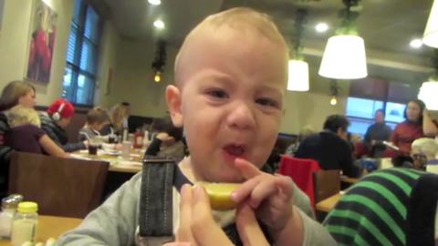 "A Baby Boy Makes A Sour Face as He Eats A Lemon"