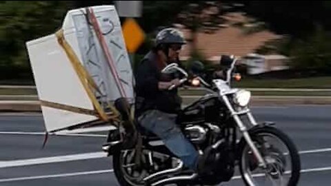 Man shifts washing machine using motorbike