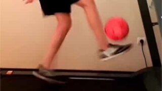 Young lad juggles soccer ball while walking treadmill