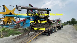 Loading rice harvester machine on a trailer in Thailand