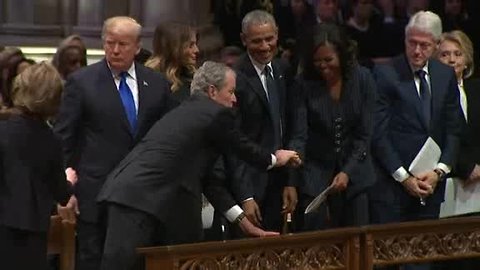 George W. Bush hands Michelle Obama a piece of candy at funeral for George H.W. Bush