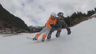 Deux amis s'essaient à un snowboard en tandem