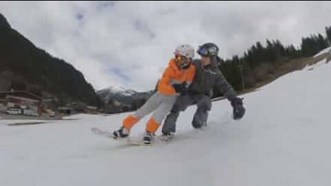 Deux amis s'essaient à un snowboard en tandem