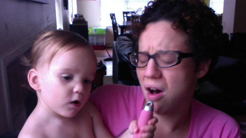 A Mom And Her Toddler Lip Sync With A Hair Brush