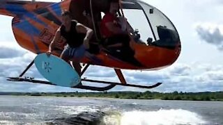 Jovem salta de helicóptero para prancha de surf