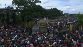 Migrant caravan breaks through border fence