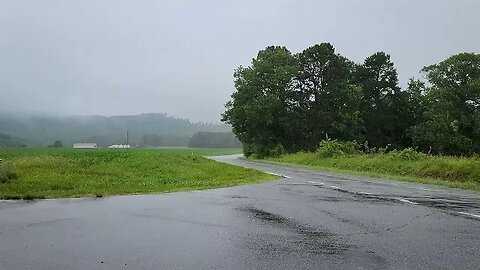 Heavy rainfall over an empty paved country road