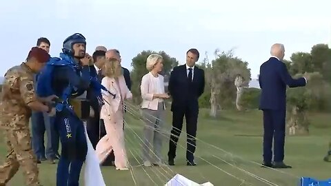 Joe Biden wandered away aimlessly as the G7 group gathered around a skydiver