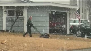Man mows his lawn during snowstorm