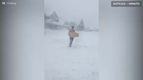 Jovem surfa na neve com traje de banho