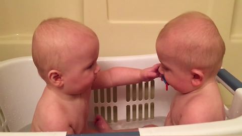 Twin Baby Boys Exchange A Pacifier From Each Other In A Bathtub