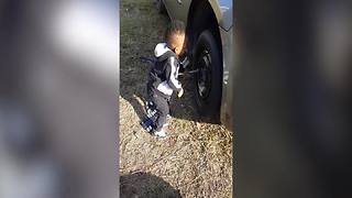 Tot Boy Fixes A Tire On A Car