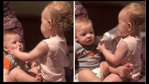 Toddler attempts to bottle feed baby brother