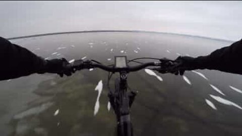 Cyclist crosses transparent frozen lake