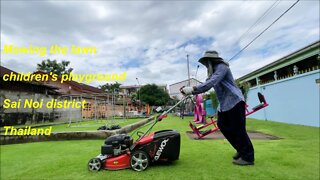 Mowing the lawn at a children's playground in Sai Noi district, Thailand