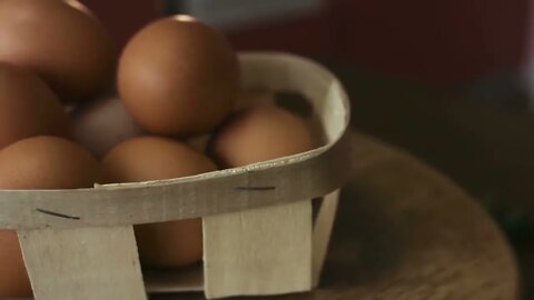 Close-up footage of basket of brown eggs lie on a wooden board which is spinning around