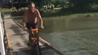 Guy performs epic lakeside bicycle jump