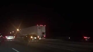 Uomo appeso a un camion che viaggia in autostrada