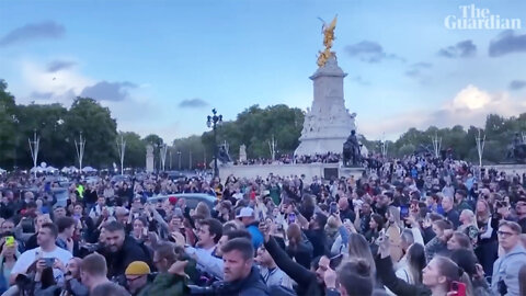 An emotional crowd sings "God Save the Queen" in front of Buckingham Palace.